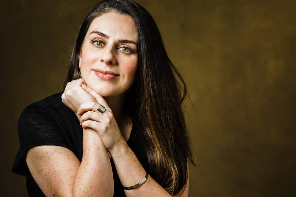 Headshots image of a woman with her hands clasped under her chin