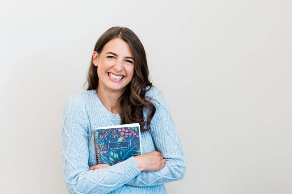 Headshots image of a woman clutching a book in her arms
