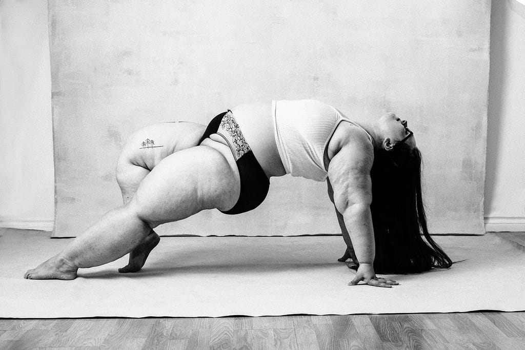 feminine embodiment boudoir image of woman wearing bralette and panties doing a bridge type pose with head and hair hanging down to floor