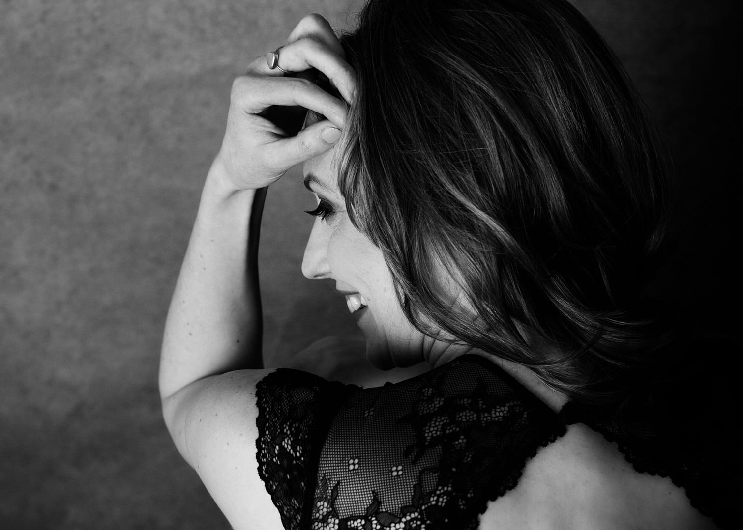 woman with hand on head and wearing black lace on shoulder