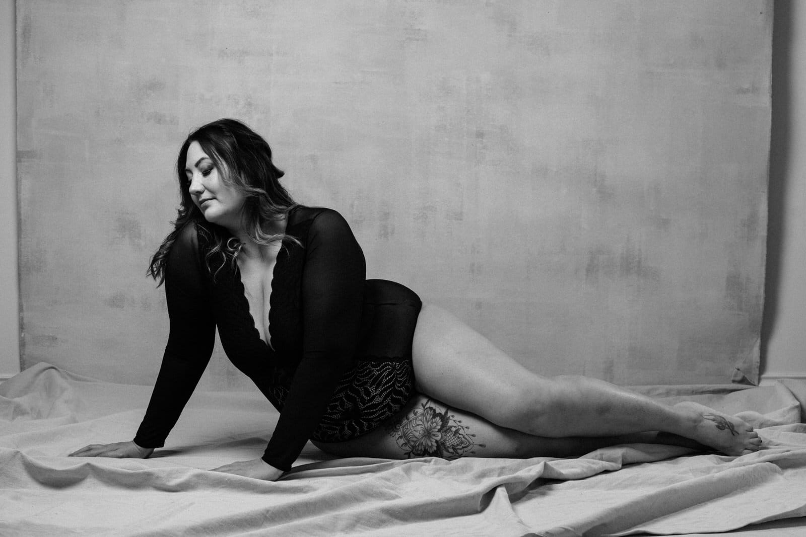 Vancouver Plus Size Boudoir, showing a woman in a black long sleeved bodysuit looking confident in her own skin. Setting is a contemporary high end boudoir studio in Vancouver.
