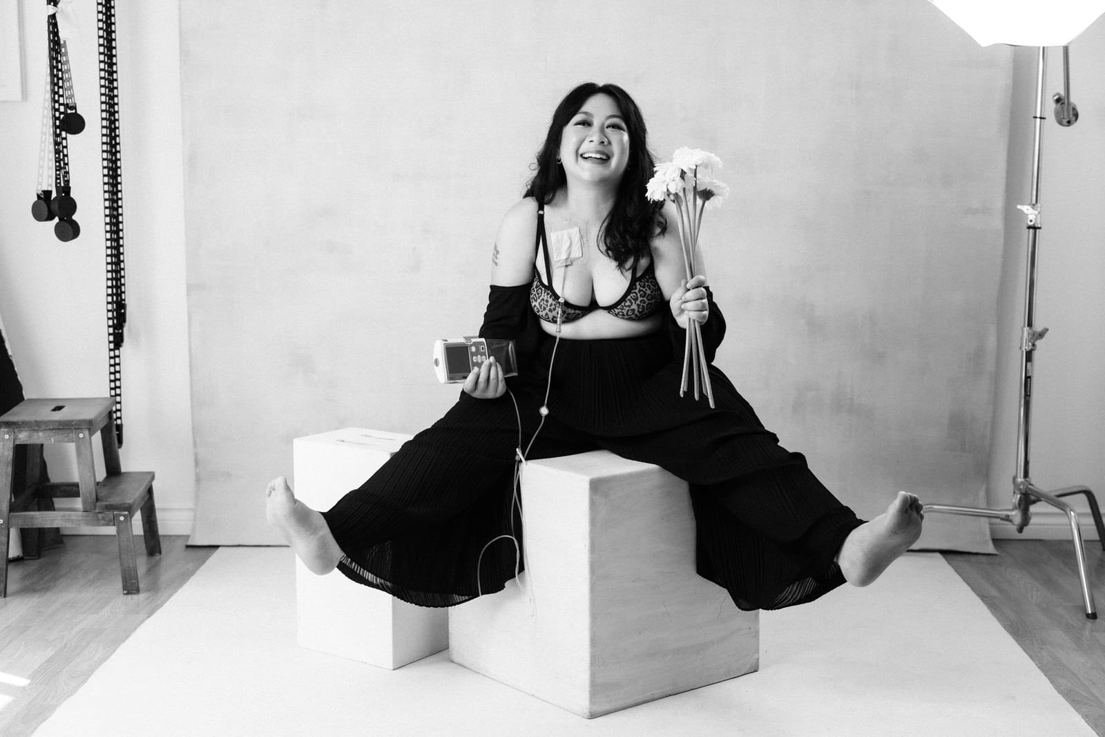 black and white image of woman showing diversity while holding flowers in one hand and medical equipment in the other hand