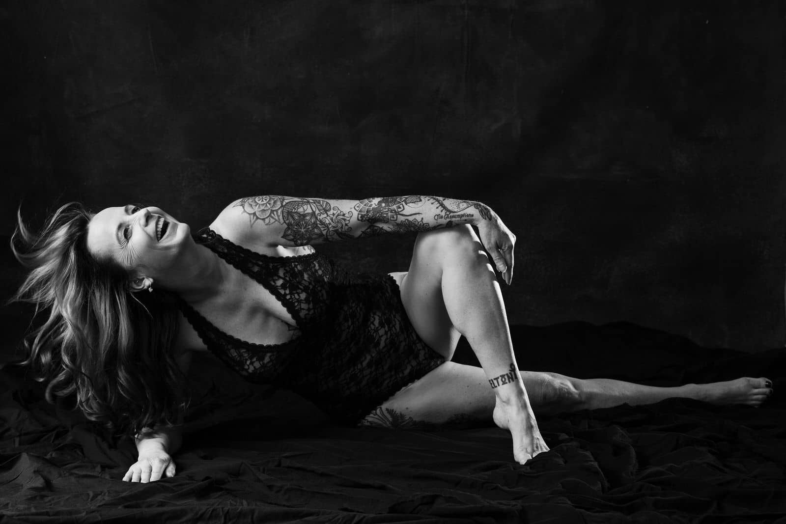 Black and white boudoir portrait of woman in lingerie laughing. Vancouver boudoir studio