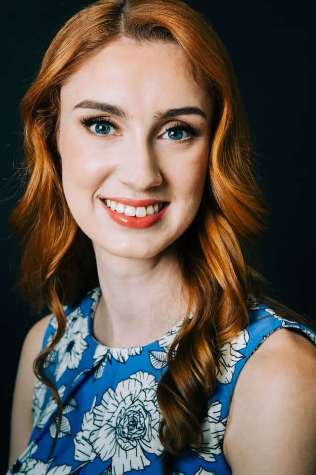Up close headshots image of a woman with red hair and blue eyes