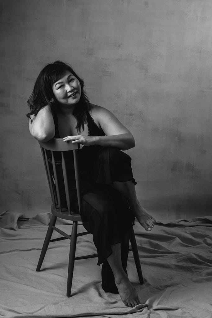 Black and white portrait of a Japanese woman on a chair with a fine art minimalist aesthetic