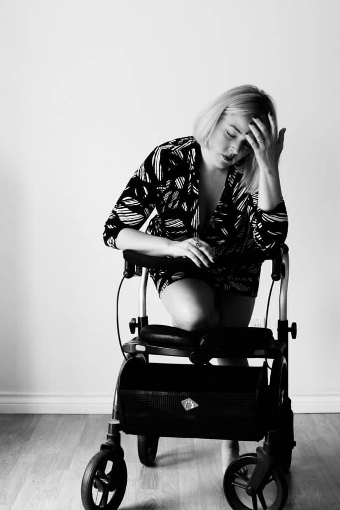 Woman kneeling on her walker holding her hand to hear head looking to be in pain