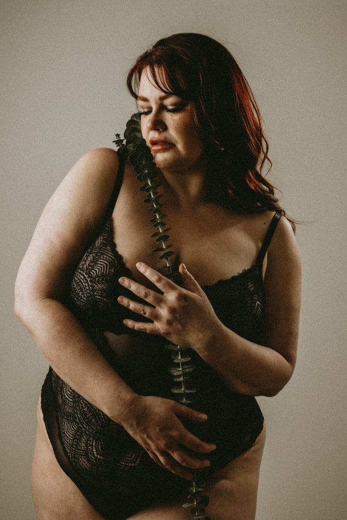 Plus size boudoir photo of a woman holding eucalyptus