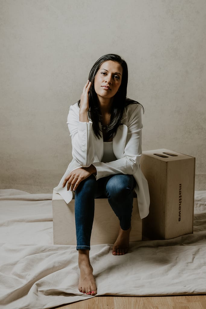 Portrait of a woman in a white blazer sitting on a stool. Coquitlam Portrait studio near me