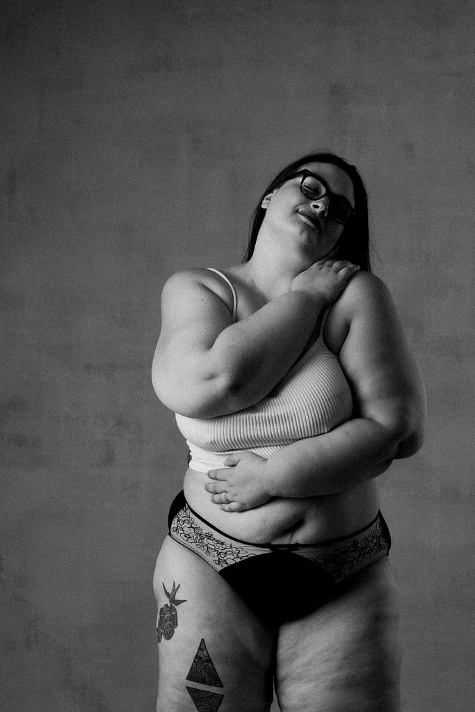 feminine embodiment boudoir image of woman wearing bra and panties hugging herself