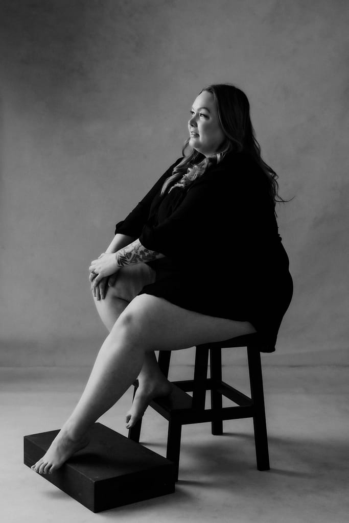Vancouver plus size inclusive boudoir photoshoot portrait of a woman sat in front of a hand painted canvas offer a classy feeling to the portrait