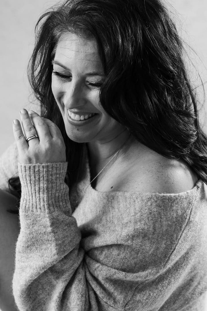 head and shoulders of woman wearing off shoulder sweater and smiling