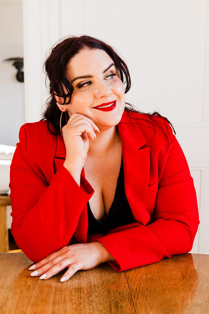Vancouver personal brand photoshoot for lawyer kathleen adams who is sat at a teak table wearing a red dress looking out the window
