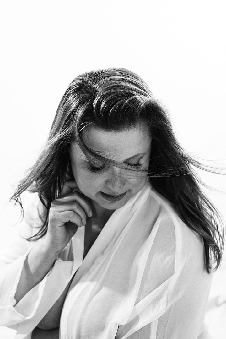 Black and white Boudoir portrait of a woman wearing open white shirt revealing cleavage