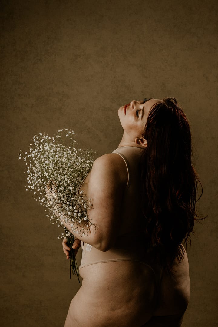 Plus size boudoir photo of a woman holding baby's breath