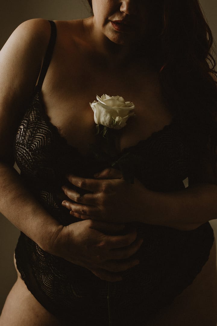 Plus size boudoir photo of a woman's mid section holding flowers