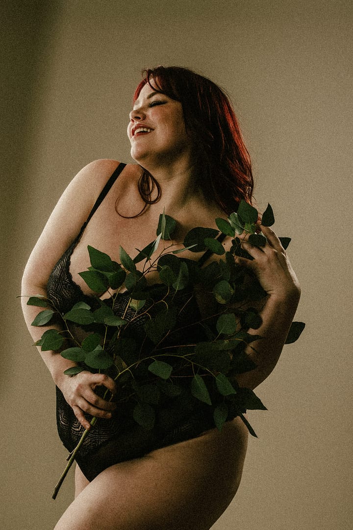 Plus size boudoir photo of a woman holding greenery