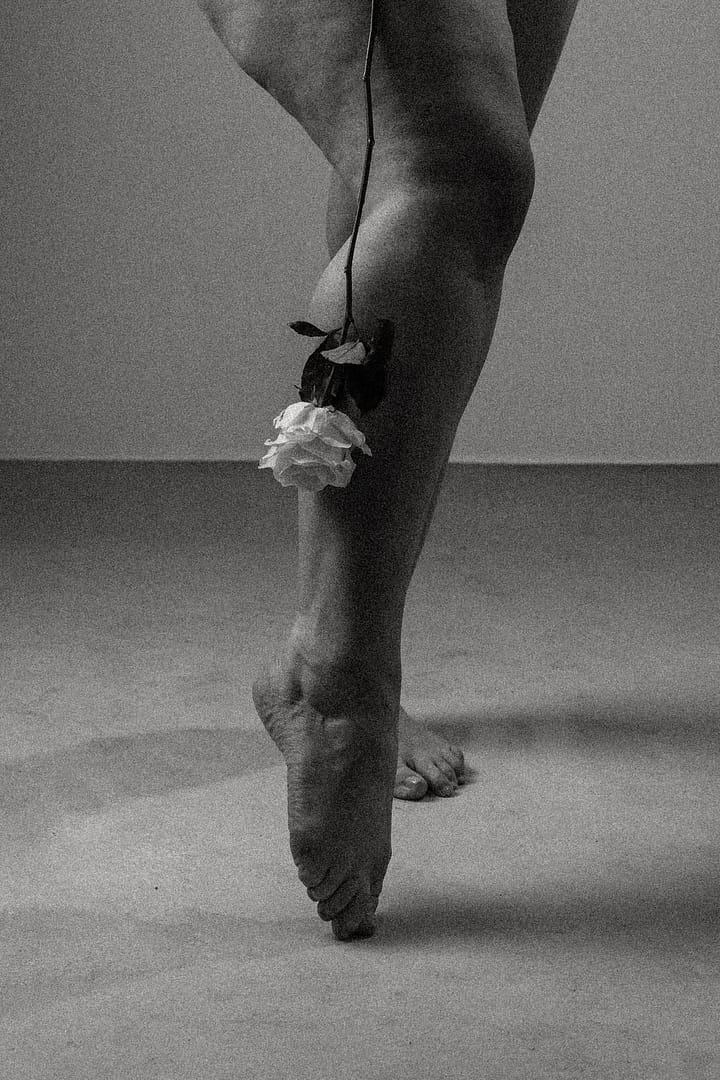 Close up of woman's legs and a rose hanging touching one leg