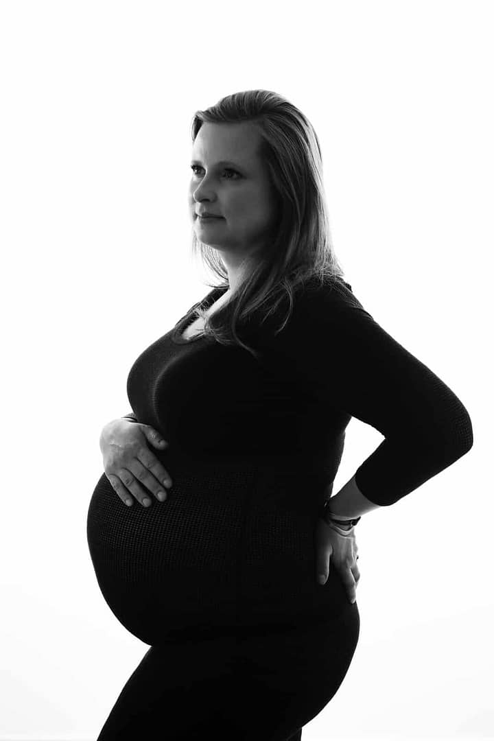 maternity boudoir image of woman wearing black dress featuring her belly by Vancouver Maternity Photographer