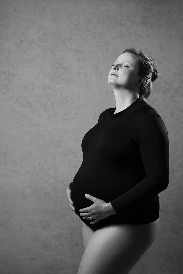 pregnant woman wearing black top holding her belly by vancouver maternity photographer Mateus Studios