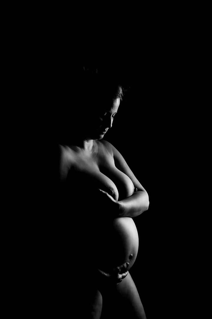 dramatic maternity photographer boudoir image of naked woman showing her pregnant body