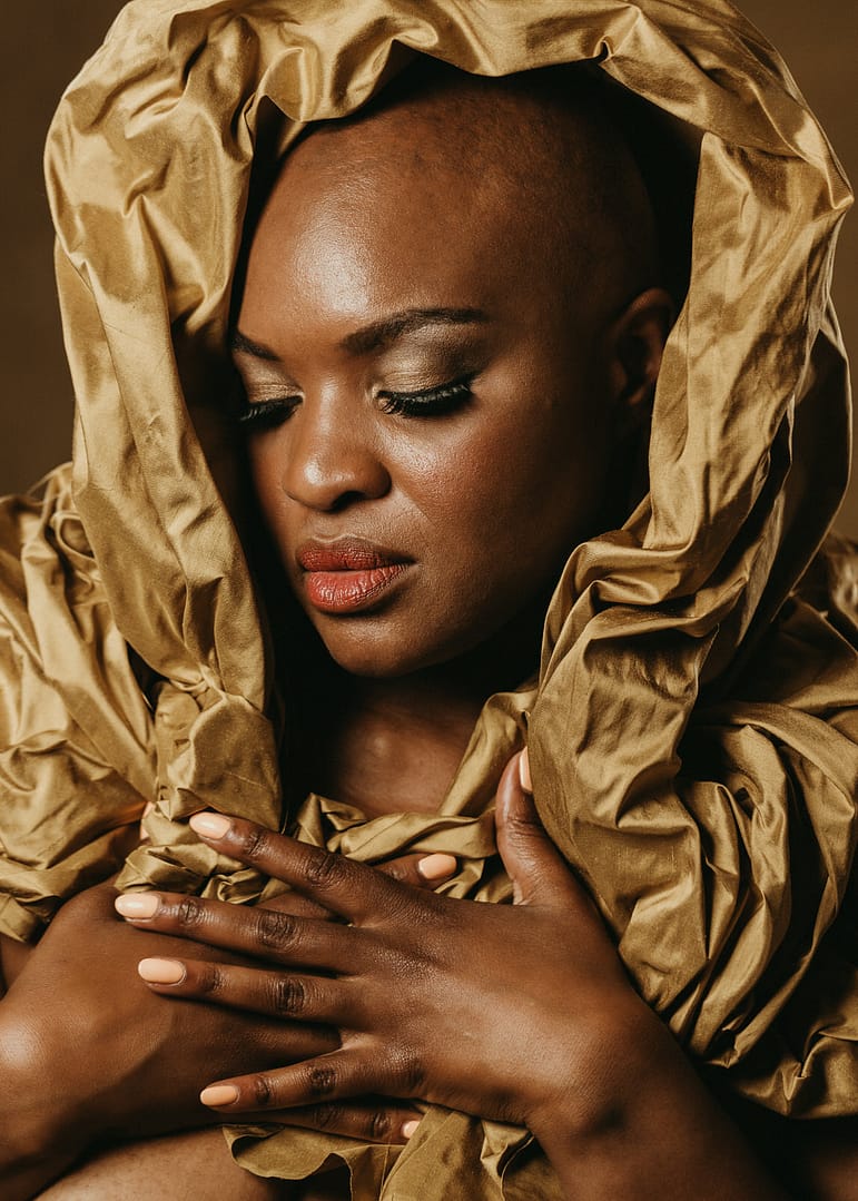 vancouver boudoir photographer image of plus size black woman with alopecia wrapped in gold fabric