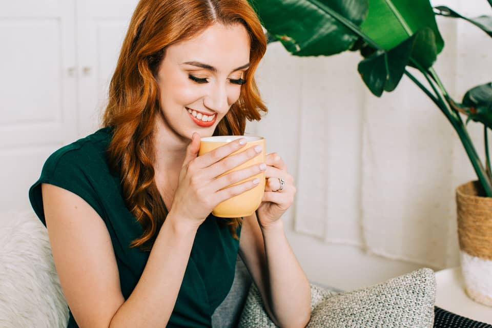 Red headed woman holding a warm mug of coffee