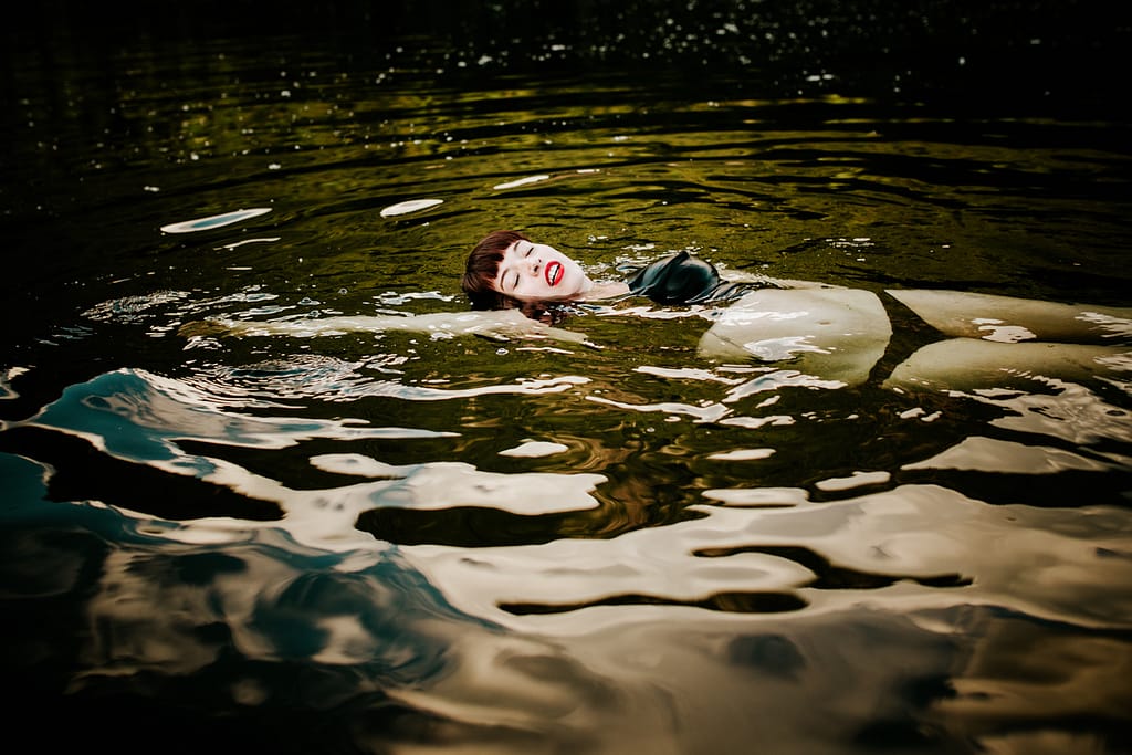 woman in black bikini floating on her back in a body of water