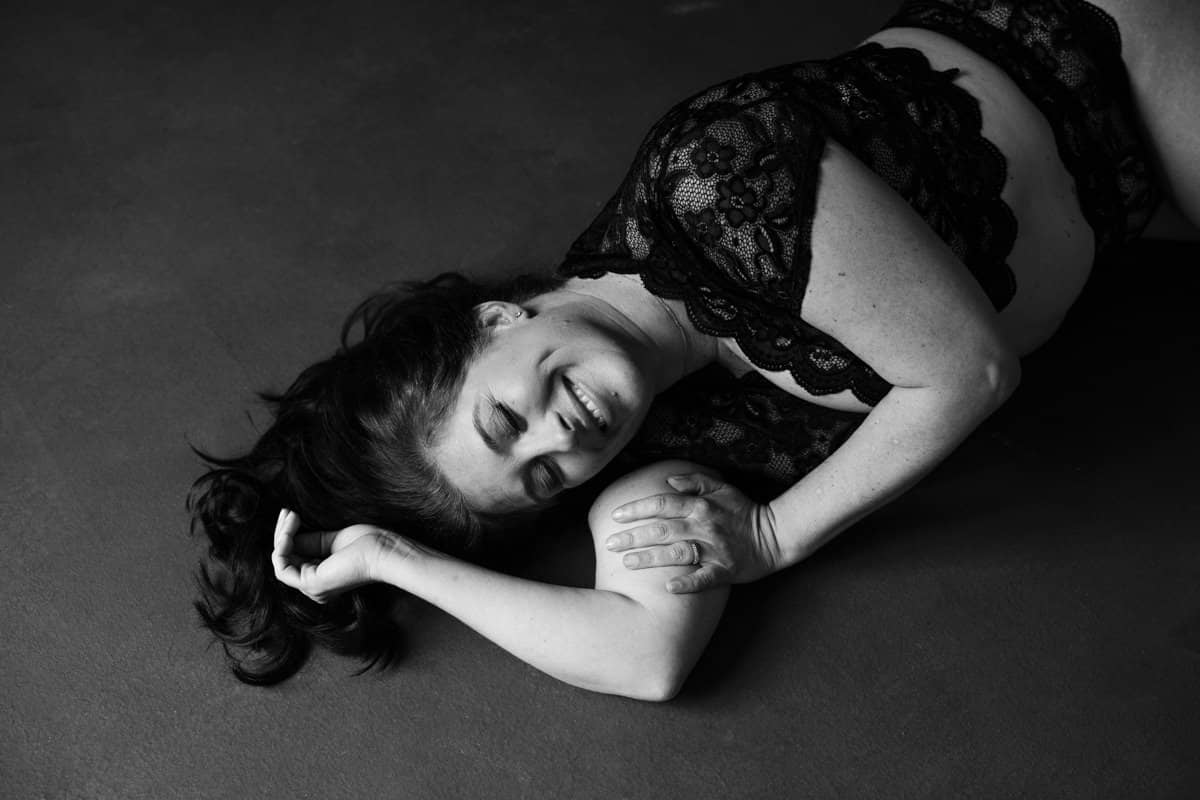 boudoir image of woma laying on floor wearing lace top