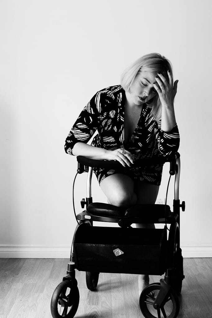 Woman kneeling on her walker holding her hand to hear head looking to be in pain
