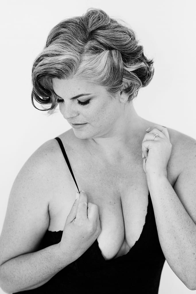 photo in black and white of woman wearing lingerie holding straps during boudoir photoshoot vancouver