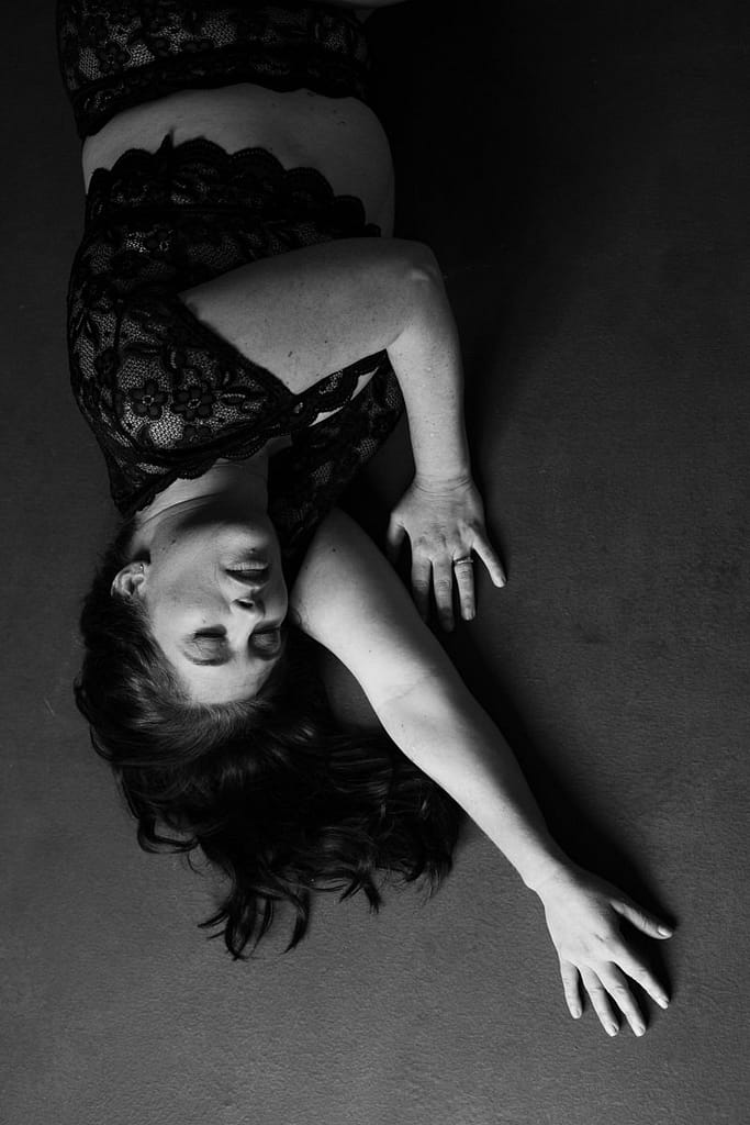 boudoir image of woman laying on floor wearing lace top