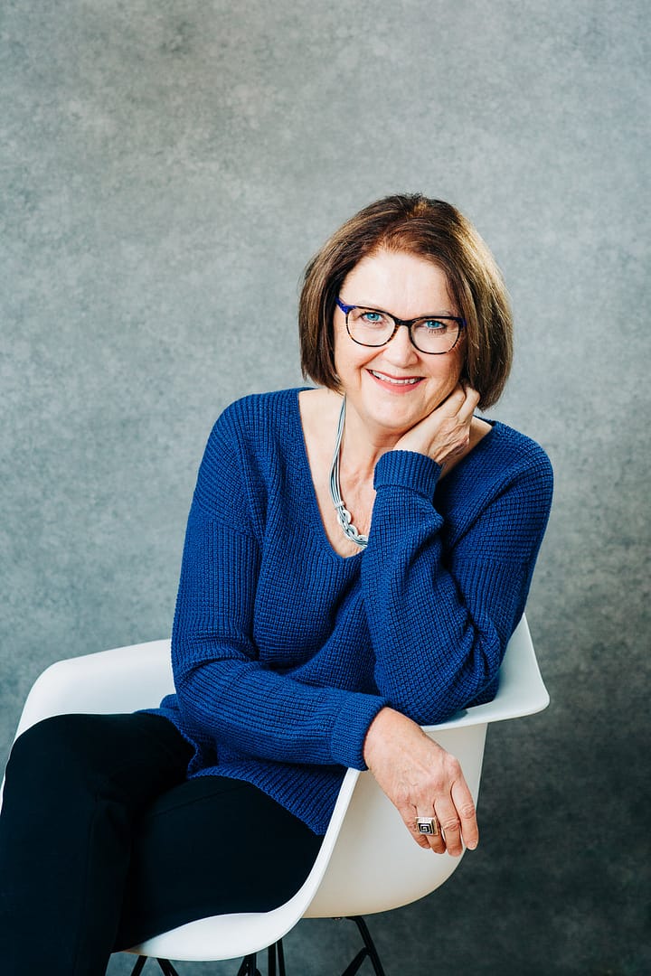 Professional headshot of elder woman with glasses sitting on a chair. Professional headshot portraits Coquitlam