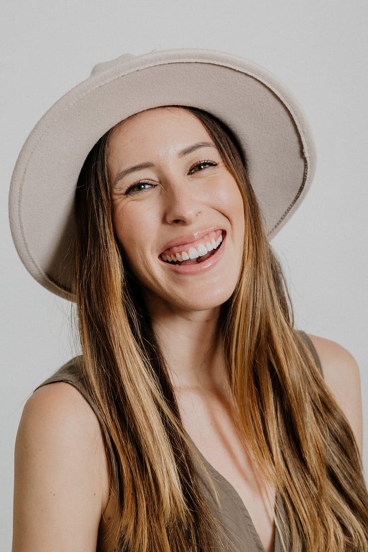 Professional headshot of woman with big hat laughing. Headshot studio vancouver.