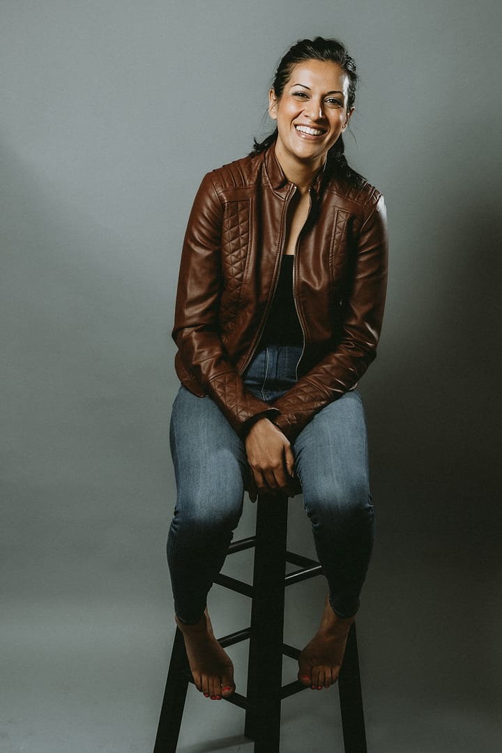 Portrait of a woman in a brown leather jacket sitting on a chair. Professional headshot photography coquitlam