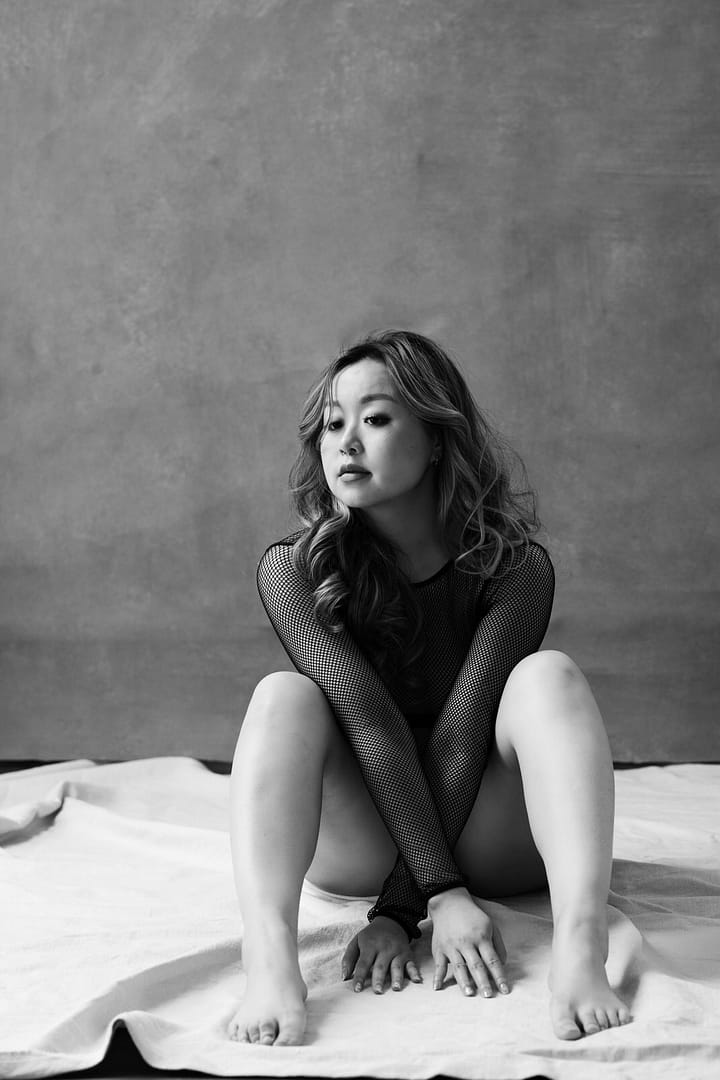Black and white boudoir photo shoot image of a woman sitting on a studio floor, Vancouver Boudoir Studio Mateus Studios