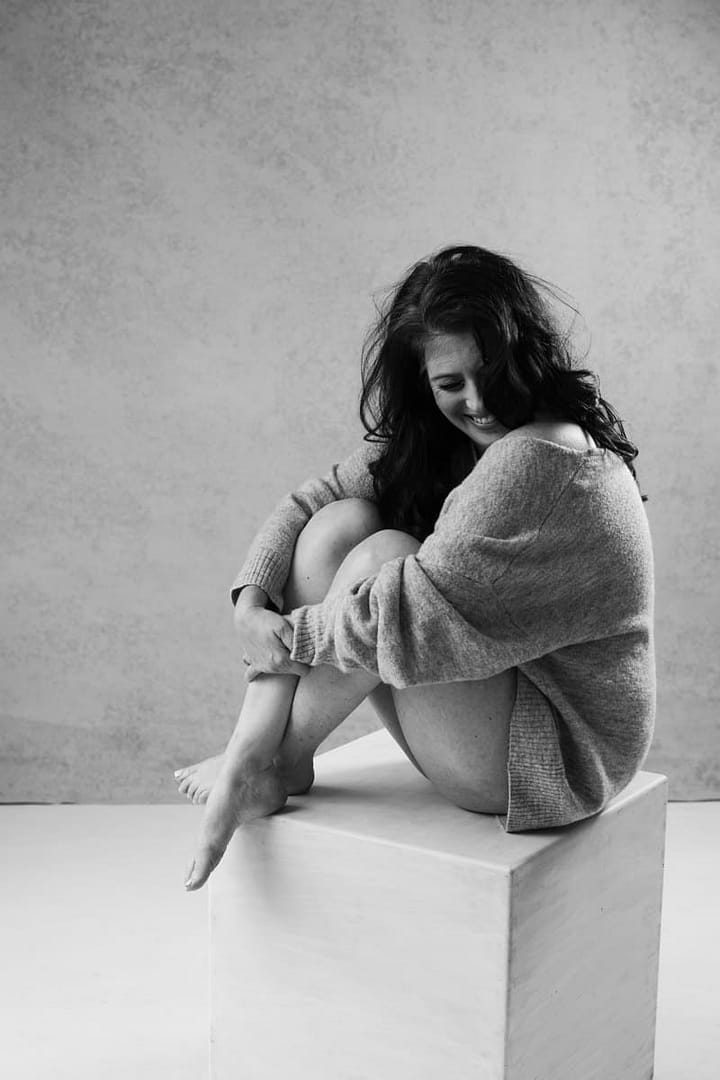 boudoir image of woman sitting and hugging legs