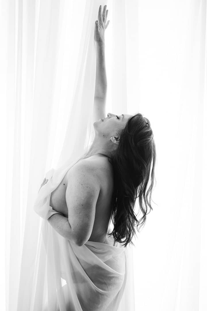 boudoir image of curvy woman draped in fabric revealing upper body