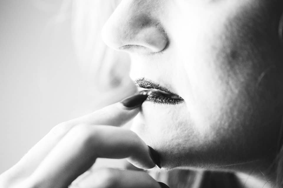 woman holding her finger to her lip in black and white boudoir image
