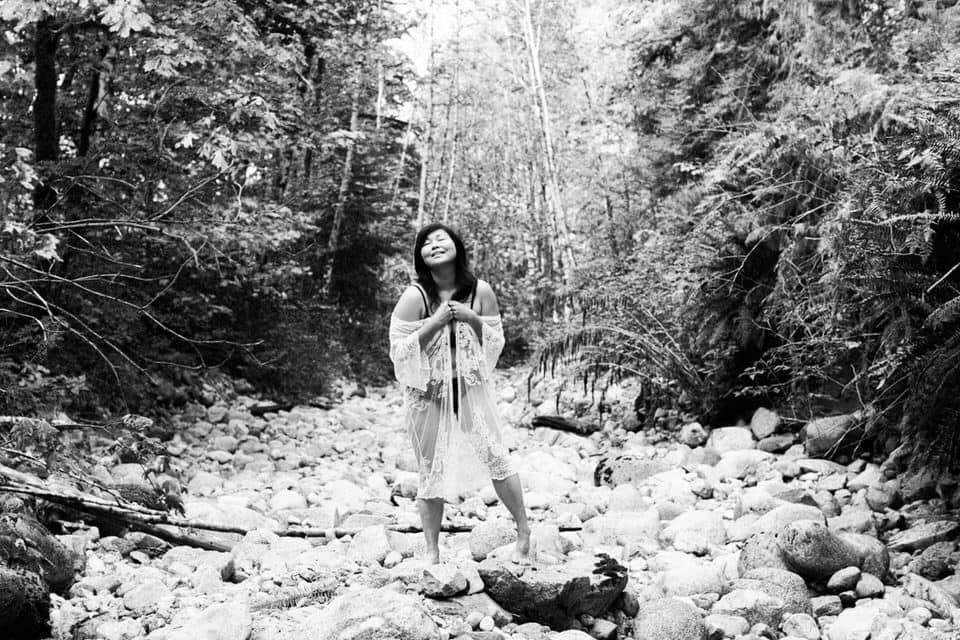 woman standing in a dry creek bed surrounded by forest wearing lingerie