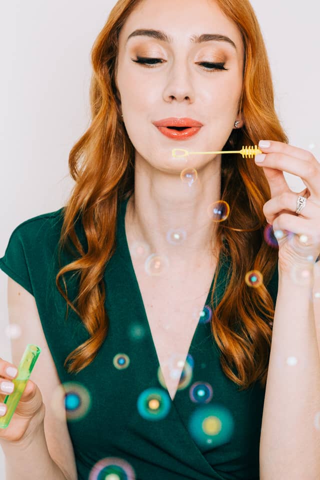 Woman with red hair blowing bubbles